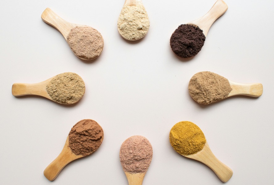 Different colored powder in wooden spoons