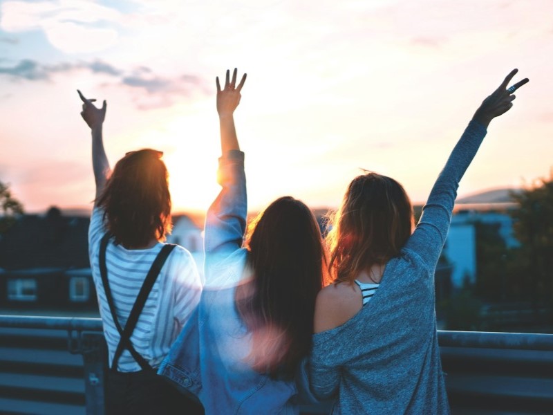 Three young women with their hands in the air